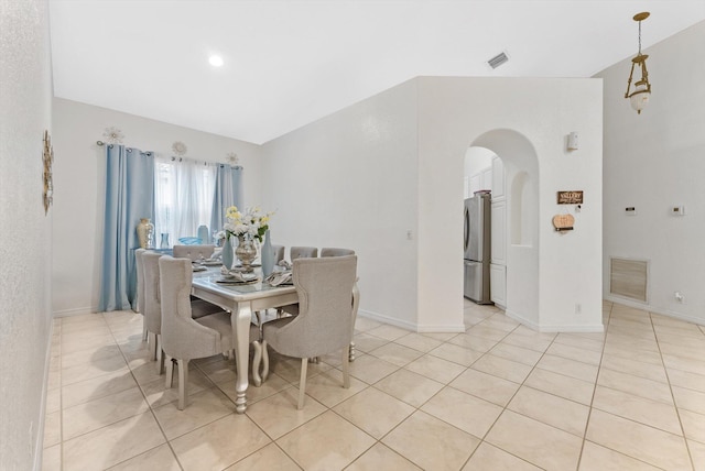 dining room featuring arched walkways, light tile patterned floors, and baseboards