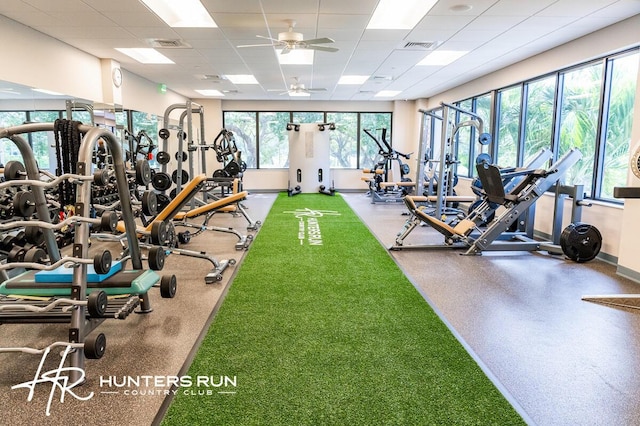 workout area featuring a drop ceiling, ceiling fan, and baseboards