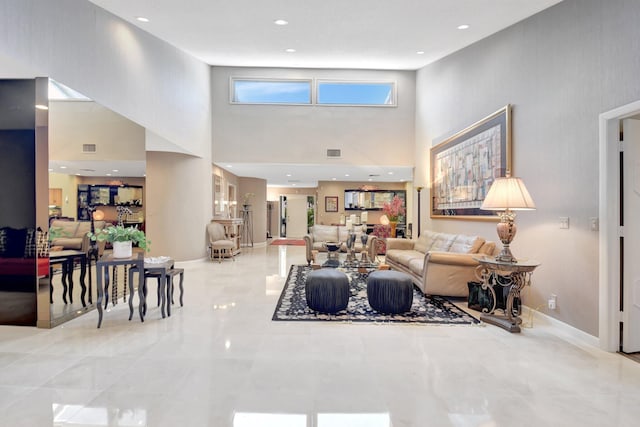 living room with a high ceiling, marble tiled floors, and baseboards