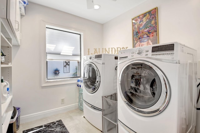 clothes washing area with cabinet space, washing machine and clothes dryer, light tile patterned floors, and baseboards