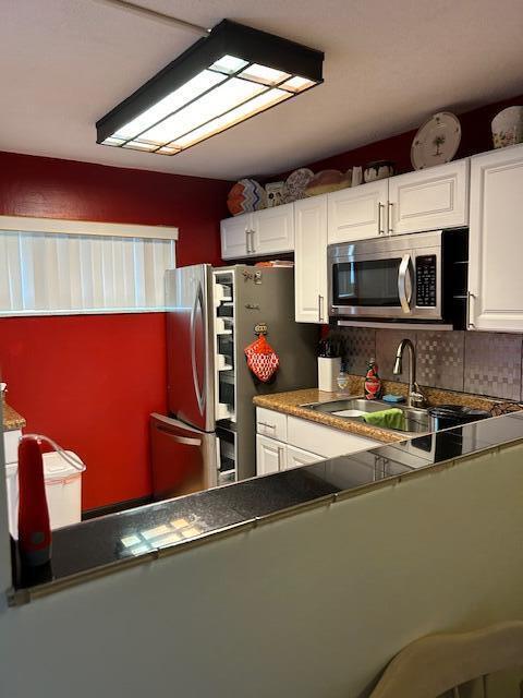 2724 S Garden Dr Unit 311, Lake Worth, FL 33461 - kitchen featuring appliances with stainless steel finishes, a sink, white cabinets, and backsplash