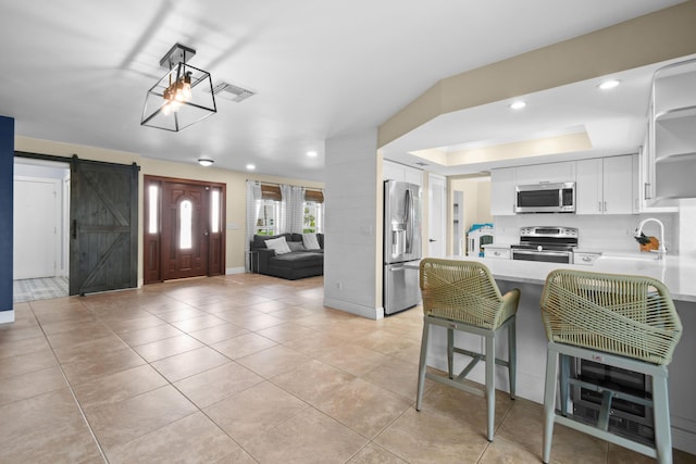 kitchen featuring appliances with stainless steel finishes, open shelves, a sink, a peninsula, and light countertops