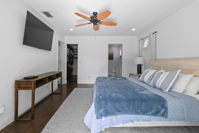 bedroom featuring dark wood finished floors, baseboards, a spacious closet, connected bathroom, and recessed lighting