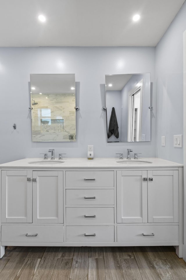 full bath with double vanity, wood finished floors, a walk in shower, and recessed lighting