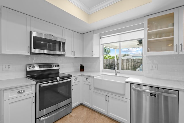 kitchen with stainless steel appliances, a sink, ornamental molding, and white cabinetry