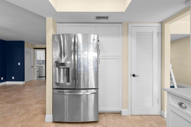 kitchen featuring stainless steel refrigerator with ice dispenser, white cabinetry, baseboards, and light tile patterned flooring