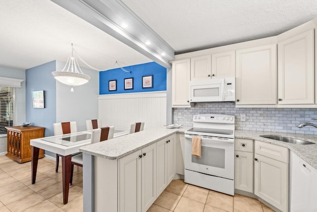 234 Pine Hov Cir Unit B-1, Greenacres, FL 33463 - kitchen featuring white appliances, a sink, a peninsula, light tile patterned floors, and hanging light fixtures