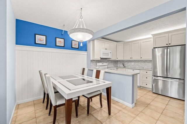 234 Pine Hov Cir Unit B-1, Greenacres, FL 33463 - kitchen featuring white appliances, a textured ceiling, a peninsula, wainscoting, and light tile patterned floors
