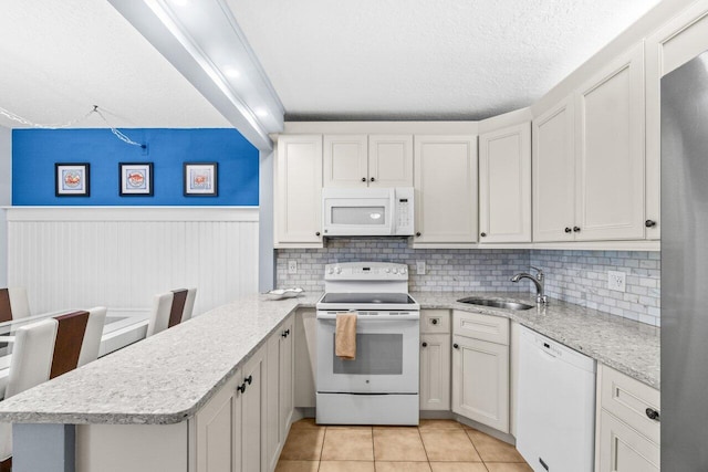 234 Pine Hov Cir Unit B-1, Greenacres, FL 33463 - kitchen featuring white appliances, a sink, a peninsula, light tile patterned flooring, and a wainscoted wall