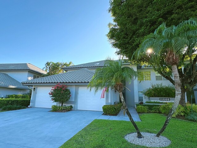 11666 Briarwood Cir Unit 1, Boynton Beach, FL 33437 - view of front of home featuring a garage, stucco siding, concrete driveway, a front yard, and a tile roof