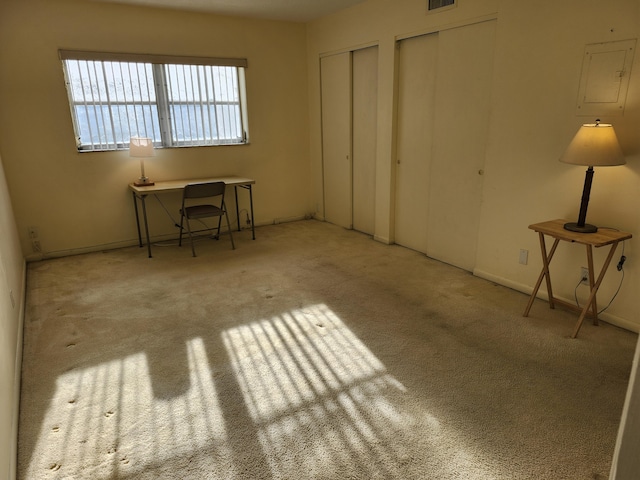 unfurnished bedroom featuring two closets, carpet floors, and baseboards