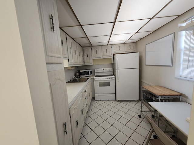 kitchen featuring white appliances, a sink, light tile patterned floors, light countertops, and a paneled ceiling