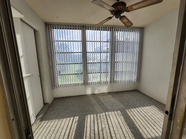 carpeted empty room featuring a ceiling fan and plenty of natural light