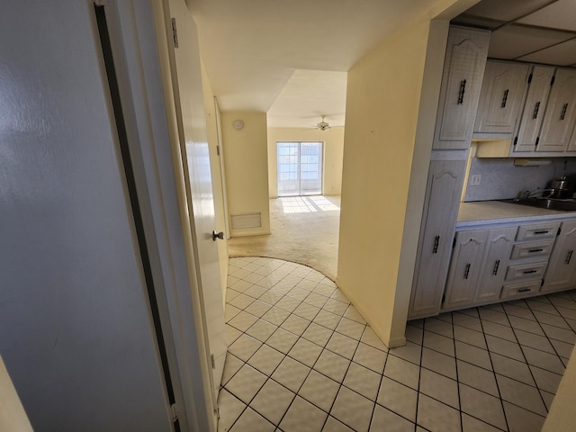 kitchen with light tile patterned flooring, light countertops, a ceiling fan, a sink, and white cabinets