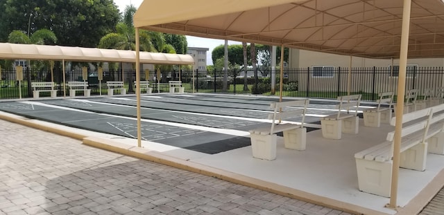 view of property's community featuring fence and shuffleboard