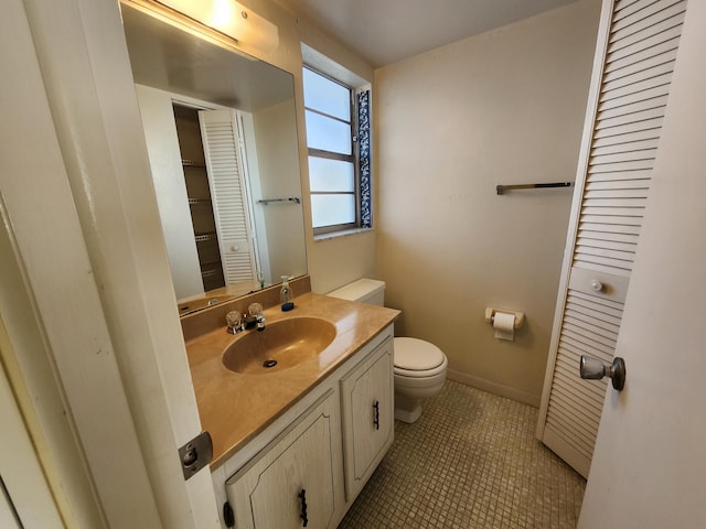 bathroom featuring toilet, a closet, vanity, and tile patterned floors