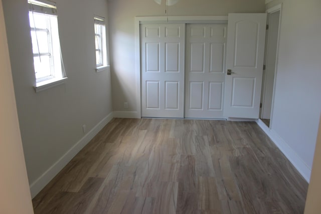 unfurnished bedroom with wood finished floors, baseboards, and a closet