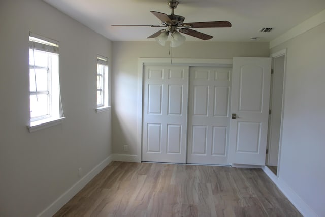 unfurnished bedroom with wood finished floors, a closet, baseboards, and a ceiling fan