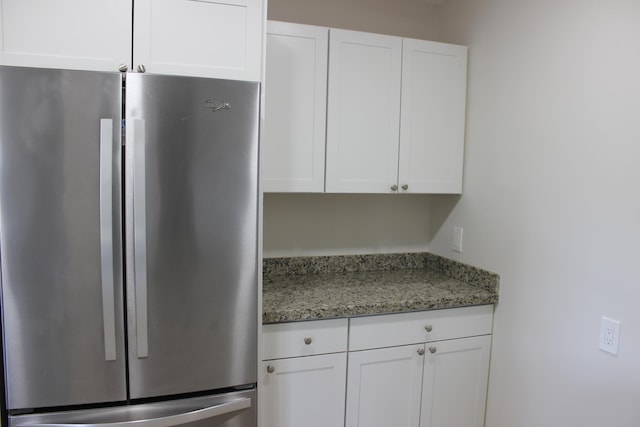 kitchen featuring freestanding refrigerator, white cabinets, and light stone countertops