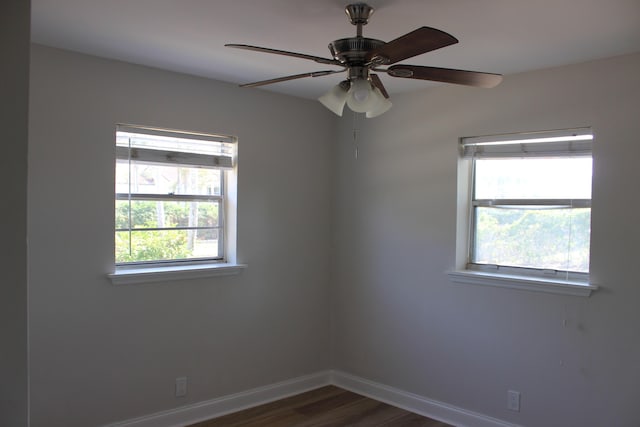 spare room with baseboards, dark wood-style floors, and a ceiling fan