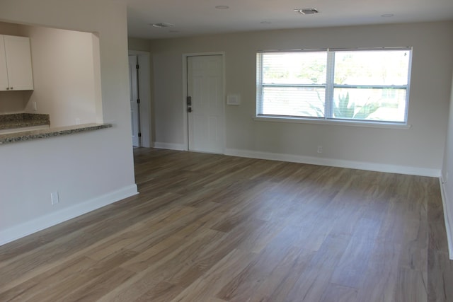 unfurnished living room with wood finished floors, baseboards, and stairs