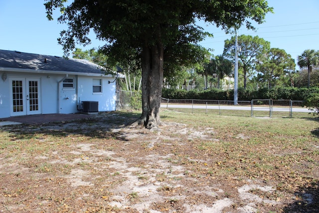view of yard with french doors, fence, central AC, and a gate