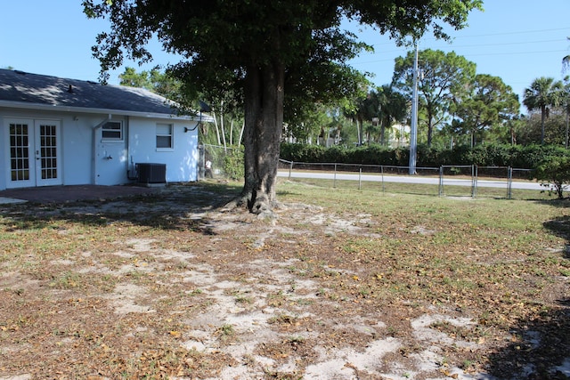 view of yard featuring french doors, fence, central AC, and a gate