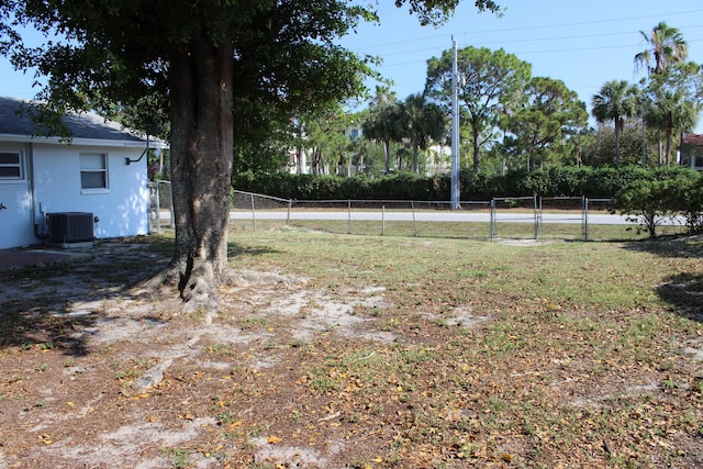 view of yard featuring central AC, fence, and a gate