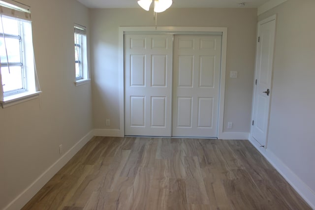 unfurnished bedroom with a closet, wood finished floors, and baseboards