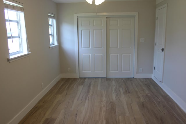 unfurnished bedroom featuring wood finished floors, a closet, and baseboards