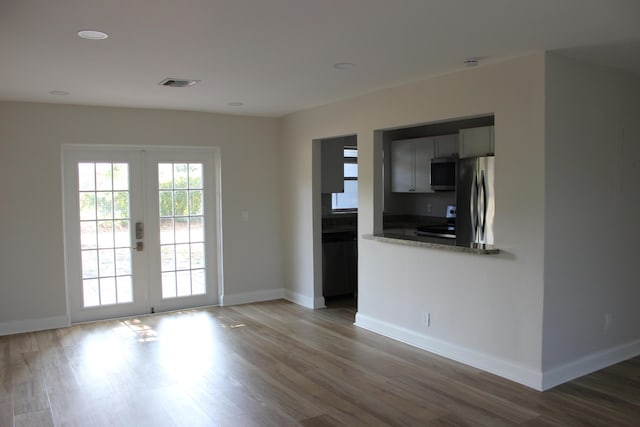 empty room featuring french doors, wood finished floors, baseboards, and recessed lighting