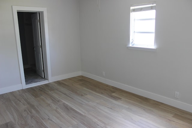 unfurnished bedroom featuring baseboards, wood finished floors, and ensuite bath