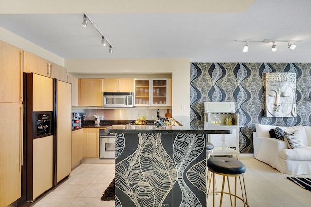 1551 N Flagler Dr Unit 804, West Palm Beach, FL 33401 - kitchen featuring stainless steel appliances, track lighting, light brown cabinets, a kitchen breakfast bar, and wallpapered walls