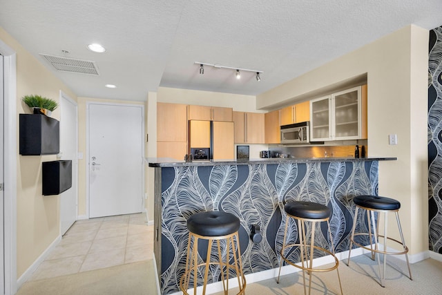 1551 N Flagler Dr Unit 804, West Palm Beach, FL 33401 - kitchen featuring stainless steel microwave, paneled refrigerator, a kitchen bar, glass insert cabinets, and baseboards
