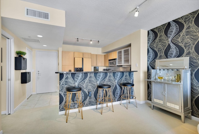 1551 N Flagler Dr Unit 804, West Palm Beach, FL 33401 - kitchen featuring stainless steel microwave, refrigerator with ice dispenser, track lighting, light brown cabinetry, and a breakfast bar area
