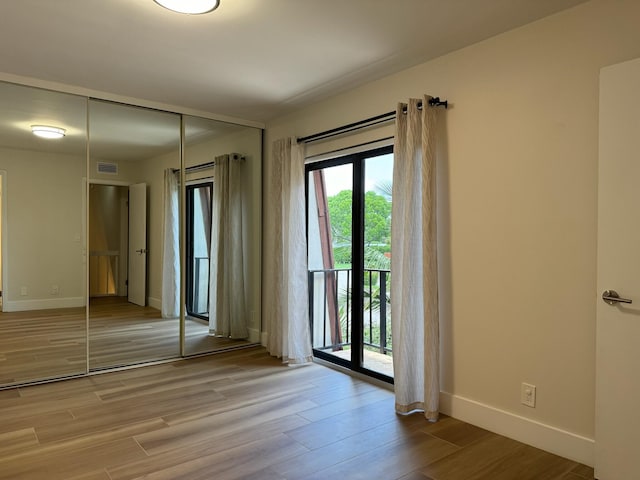 3400 Spanish Wells Dr Unit 52-C, Delray Beach, FL 33445 - unfurnished bedroom featuring access to outside, a closet, baseboards, and light wood-style flooring