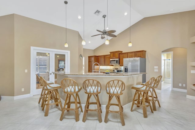 3020 SE St Lucie Blvd, Stuart, FL 34997 - kitchen with appliances with stainless steel finishes, arched walkways, brown cabinets, ceiling fan, and a kitchen bar