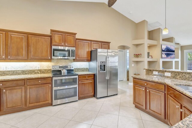 3020 SE St Lucie Blvd, Stuart, FL 34997 - kitchen featuring stainless steel appliances, high vaulted ceiling, brown cabinetry, light tile patterned floors, and decorative backsplash