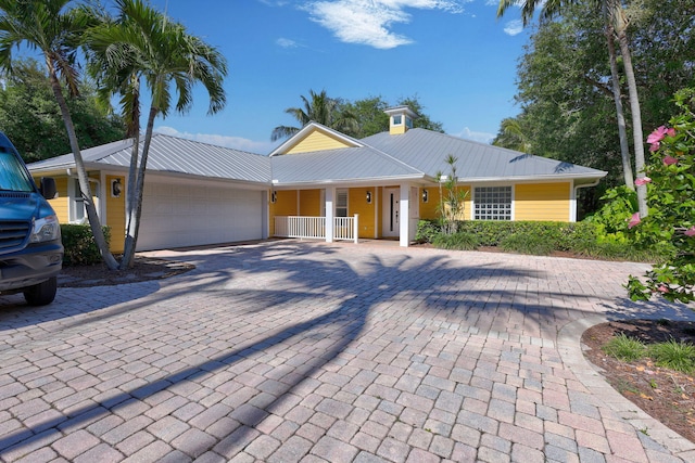 3020 SE St Lucie Blvd, Stuart, FL 34997 - view of front of home featuring covered porch, a garage, decorative driveway, and metal roof