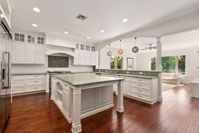 12891 Inshore Dr, Palm Beach Gardens, FL 33410 - kitchen featuring a peninsula, ornate columns, decorative backsplash, open floor plan, and white cabinetry