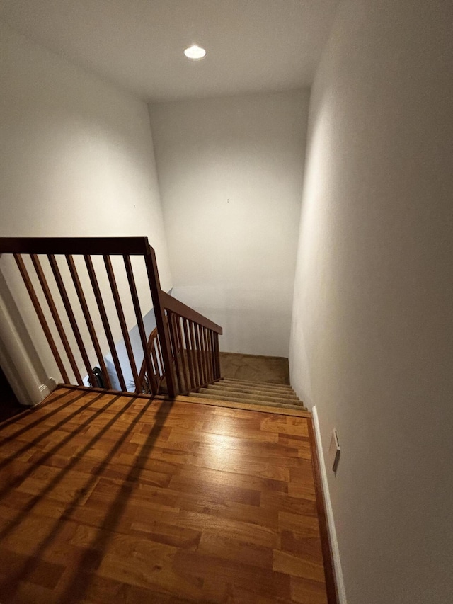 stairway with wood finished floors and recessed lighting