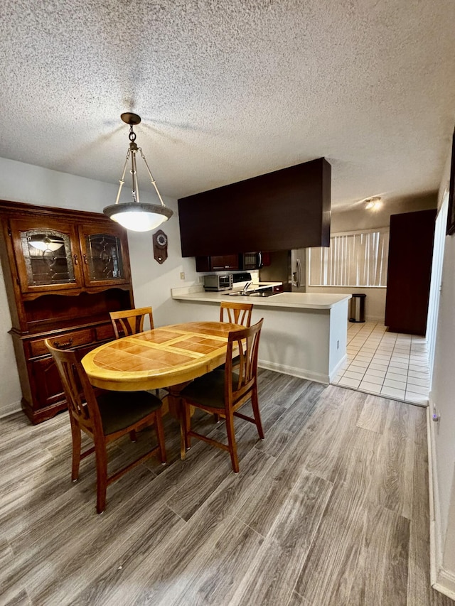 dining room featuring light wood-style flooring and a textured ceiling