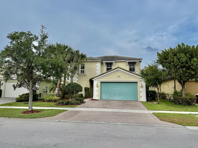 view of front of property featuring decorative driveway, a front lawn, stucco siding, and an attached garage