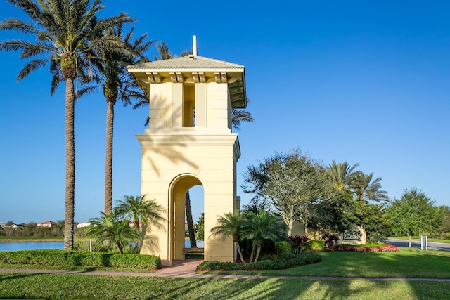 view of front of property featuring a front lawn, stucco siding, a tiled roof, and a water view
