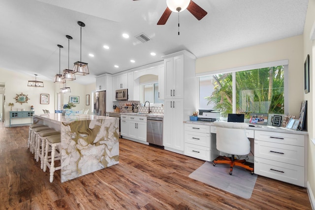 7884 Travlers Tree Dr, Boca Raton, FL 33433 - kitchen featuring stainless steel appliances, a sink, a breakfast bar area, a ceiling fan, and white cabinetry