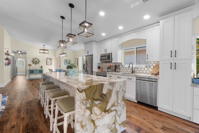 7884 Travlers Tree Dr, Boca Raton, FL 33433 - kitchen with stainless steel appliances, a sink, a center island, tasteful backsplash, and white cabinetry