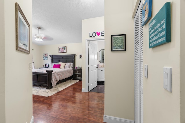 7884 Travlers Tree Dr, Boca Raton, FL 33433 - bedroom with wood finished floors, a textured ceiling, baseboards, and connected bathroom