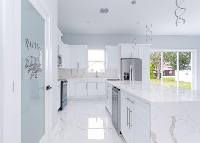 5853 NW Culebra Ave, Port Saint Lucie, FL 34986 - kitchen with stainless steel appliances, a spacious island, light marble finish flooring, white cabinetry, and a sink
