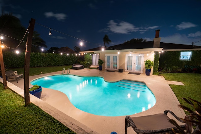 pool at twilight featuring french doors, a patio area, and a lawn