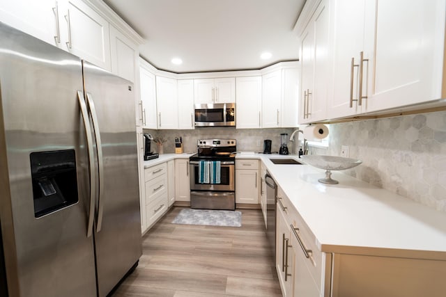 kitchen with stainless steel appliances, a sink, light countertops, recessed lighting, and light wood-style floors